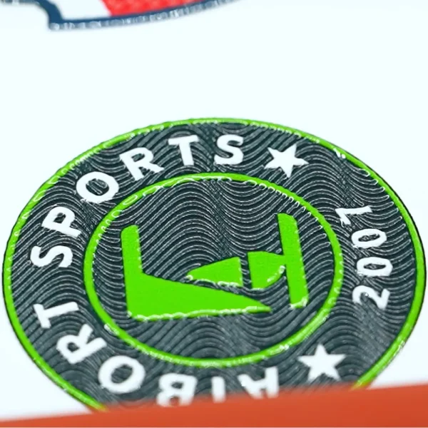 Zbliżenie zielono-czarnego emblematu UV 3D — wypukłe litery, falista faktura i połysk